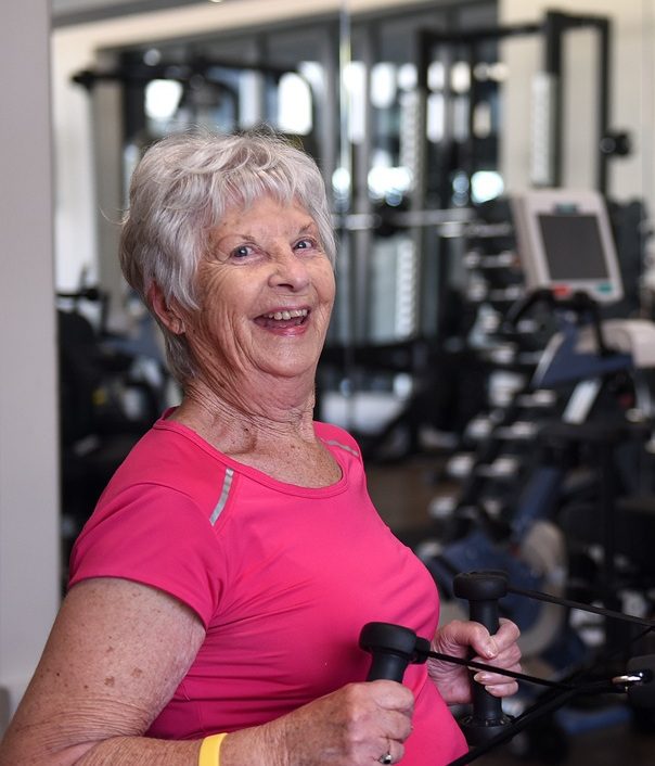 Lady wearing a pink top on the rowing machine at Wixams Village gym